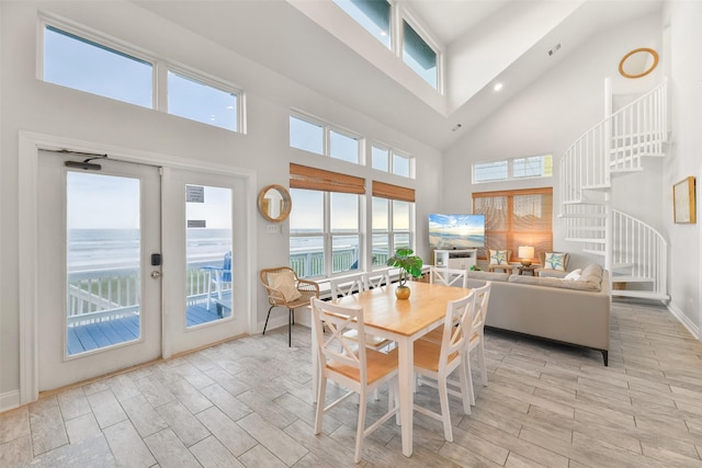 dining area with high vaulted ceiling, a water view, stairs, french doors, and wood tiled floor