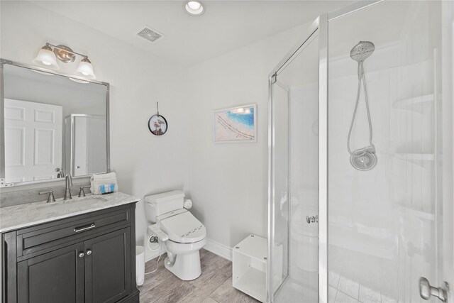 full bathroom featuring toilet, a stall shower, vanity, and visible vents