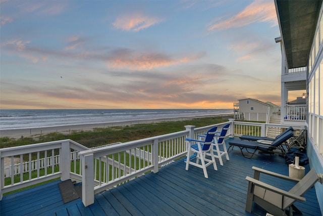 wooden terrace featuring a water view and a beach view