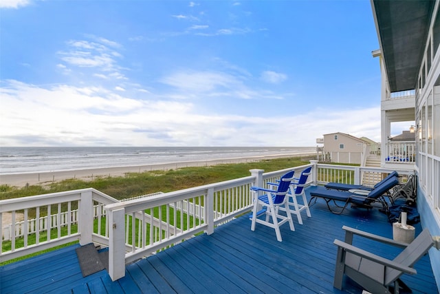 wooden deck featuring a beach view and a water view