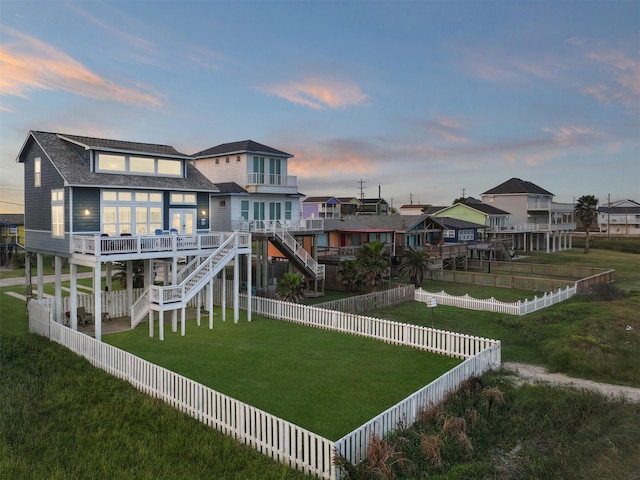 back of property at dusk with a deck, stairway, and a fenced backyard