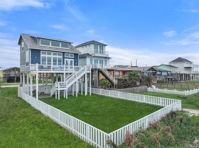 exterior space featuring a fenced backyard, stairs, a lawn, and a shingled roof