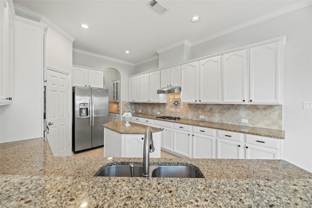 kitchen featuring decorative backsplash, white cabinets, appliances with stainless steel finishes, and light stone countertops