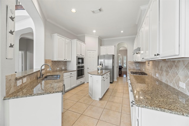 kitchen with sink, a center island, dark stone counters, and stainless steel appliances