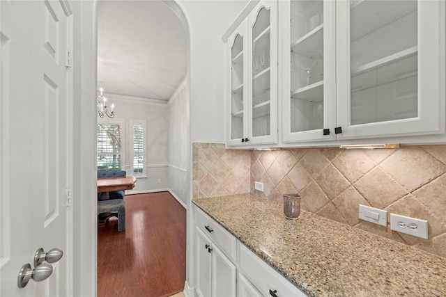 kitchen featuring white cabinets, light stone countertops, and ornamental molding