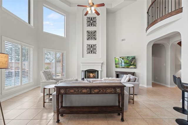 living room featuring ceiling fan, a high ceiling, and light tile patterned floors