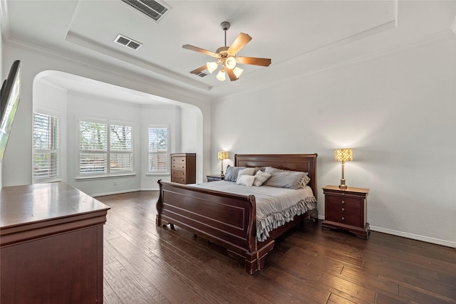 bedroom with ceiling fan, a tray ceiling, dark hardwood / wood-style floors, and ornamental molding