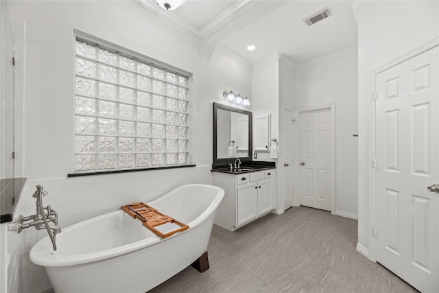 bathroom featuring a bathing tub, vanity, and ornamental molding