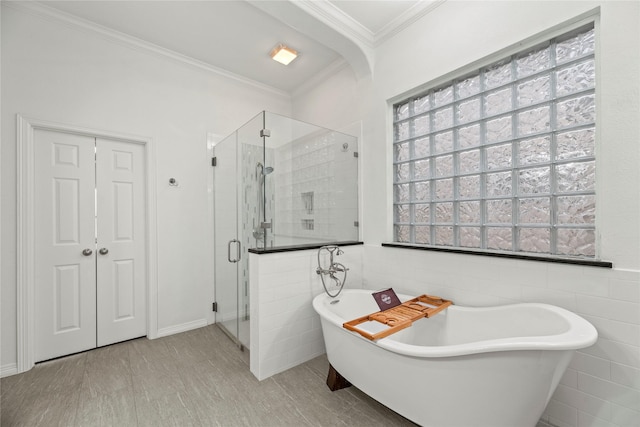 bathroom featuring a wealth of natural light, ornamental molding, tile walls, and independent shower and bath