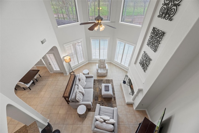 tiled living room with a high ceiling and ceiling fan