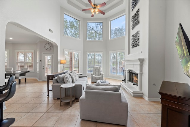 tiled living room with ceiling fan and a high ceiling