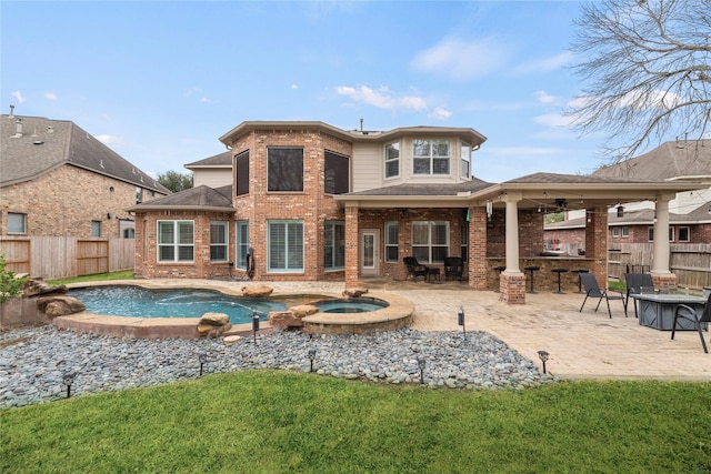 rear view of property featuring a patio, a swimming pool with hot tub, a lawn, and exterior bar