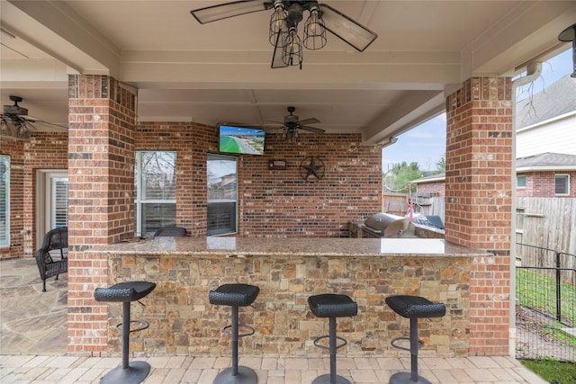 view of patio with ceiling fan, an outdoor bar, and area for grilling