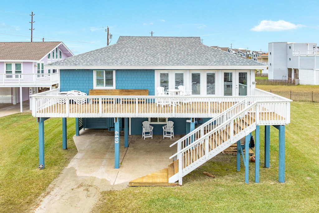 back of house with a wooden deck, a yard, and a carport