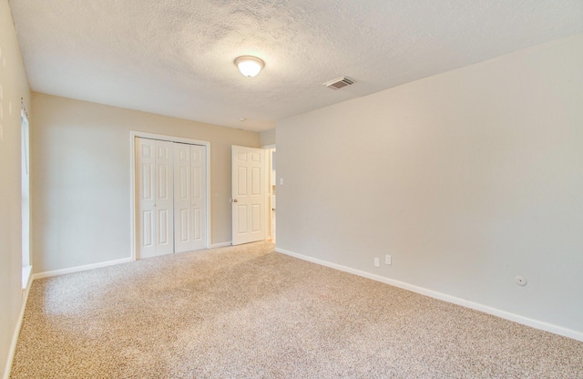 unfurnished bedroom with carpet, a closet, and a textured ceiling