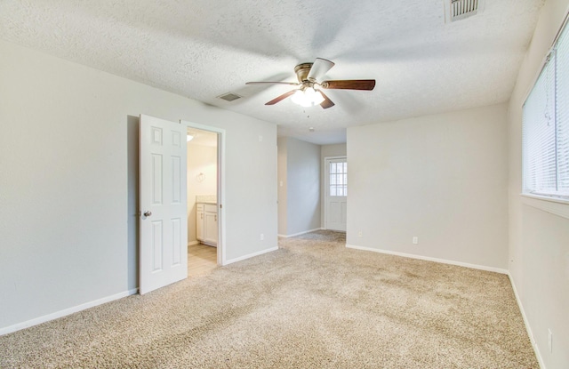 carpeted spare room featuring ceiling fan and a textured ceiling