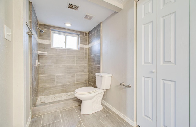 bathroom with toilet and a tile shower