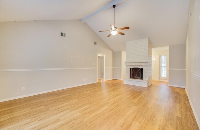 unfurnished living room with ceiling fan, beam ceiling, high vaulted ceiling, a brick fireplace, and light wood-type flooring