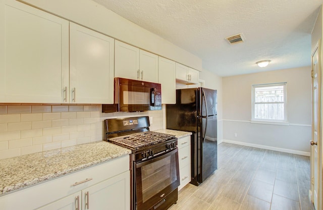 kitchen with white cabinetry, light stone countertops, black appliances, a textured ceiling, and decorative backsplash