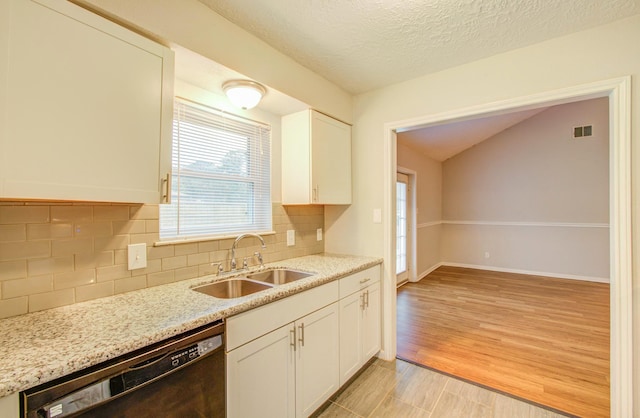 kitchen featuring sink, tasteful backsplash, light stone counters, black dishwasher, and white cabinets