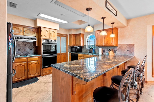 kitchen featuring light tile patterned flooring, a breakfast bar, pendant lighting, kitchen peninsula, and black appliances