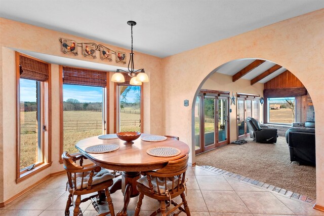 tiled dining space featuring a chandelier and lofted ceiling with beams