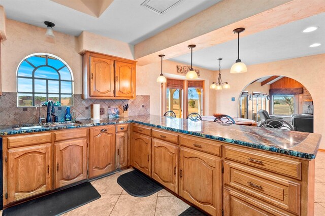 kitchen with pendant lighting, kitchen peninsula, sink, and decorative backsplash