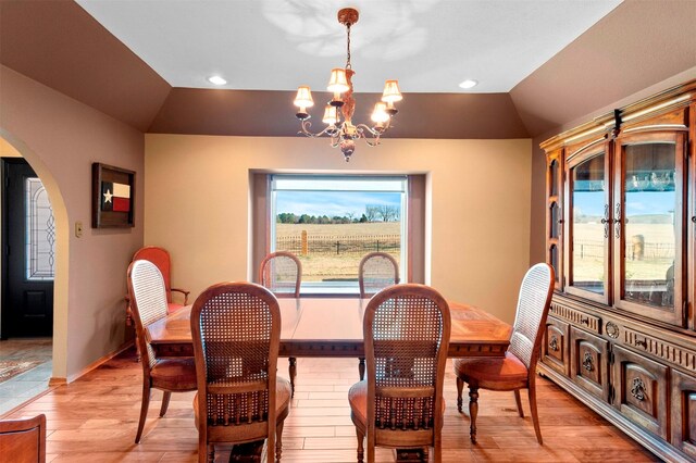 dining space with vaulted ceiling, a notable chandelier, and light hardwood / wood-style floors