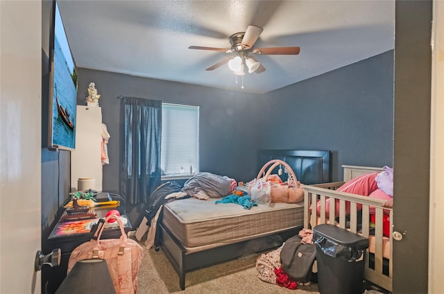 carpeted bedroom featuring ceiling fan and a textured ceiling