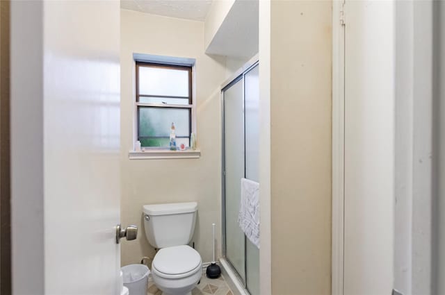 bathroom featuring a textured ceiling, toilet, and an enclosed shower