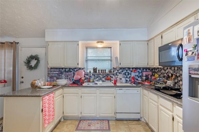 kitchen featuring kitchen peninsula, stainless steel fridge, white dishwasher, sink, and tasteful backsplash