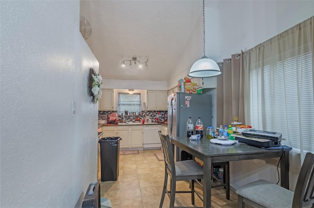 kitchen with dishwasher, hanging light fixtures, decorative backsplash, lofted ceiling, and stainless steel refrigerator