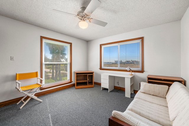 living area with ceiling fan, a textured ceiling, and dark carpet