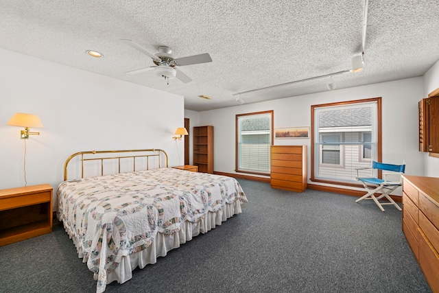 carpeted bedroom with a textured ceiling, track lighting, and ceiling fan