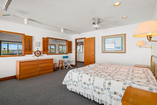 bedroom featuring a textured ceiling, rail lighting, ceiling fan, and dark colored carpet