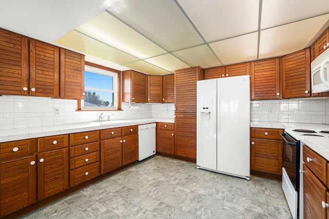 kitchen featuring tasteful backsplash, white appliances, a paneled ceiling, and sink