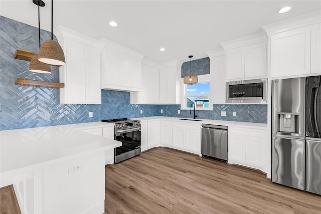 kitchen featuring sink, white cabinetry, hanging light fixtures, light hardwood / wood-style flooring, and appliances with stainless steel finishes