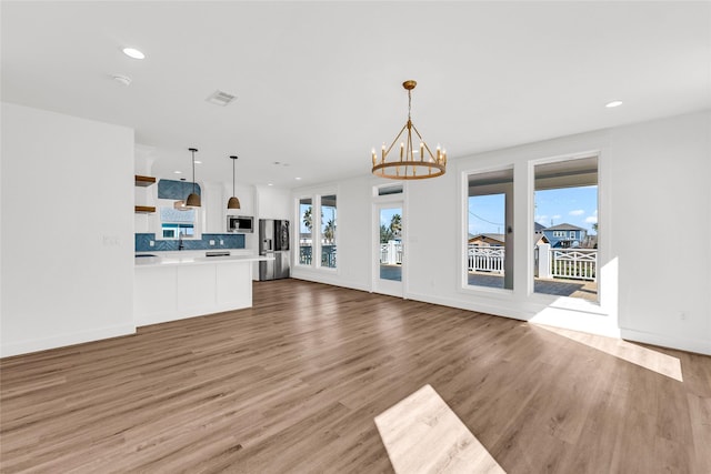 unfurnished living room with light hardwood / wood-style floors and a notable chandelier