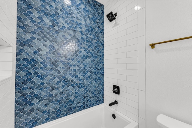 bathroom featuring toilet and tiled shower / bath