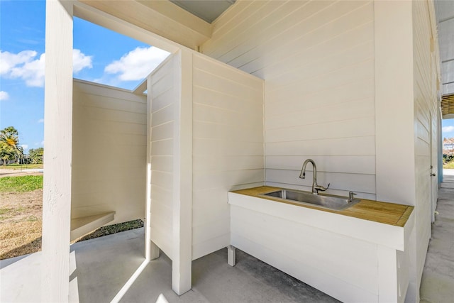 bathroom with sink, wooden walls, and concrete flooring