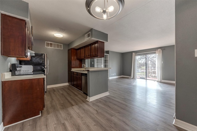 kitchen featuring a notable chandelier, a textured ceiling, stainless steel dishwasher, light wood-type flooring, and sink