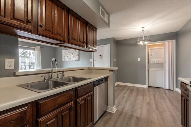 kitchen with pendant lighting, dishwasher, stacked washer and dryer, sink, and light wood-type flooring