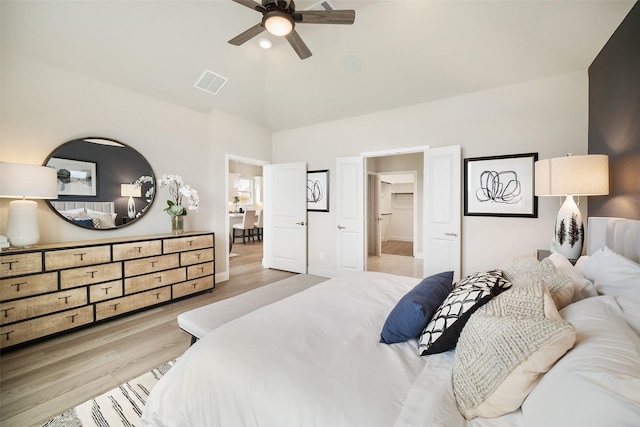 bedroom with light wood-type flooring, visible vents, and vaulted ceiling