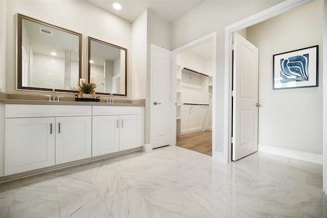 bathroom with marble finish floor, visible vents, a walk in closet, and a sink