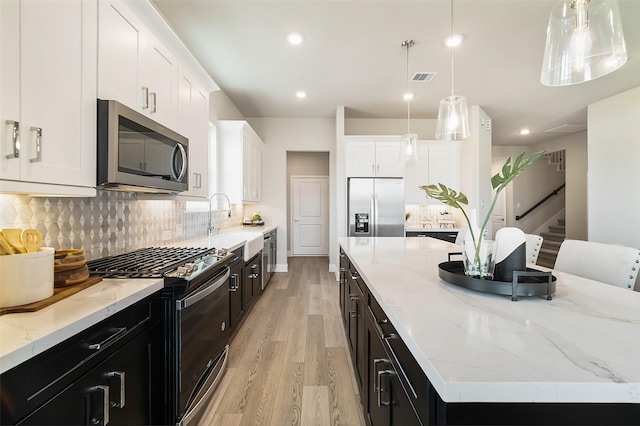 kitchen featuring white cabinetry, appliances with stainless steel finishes, pendant lighting, and a center island