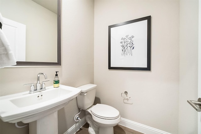 bathroom featuring wood finished floors, a sink, toilet, and baseboards