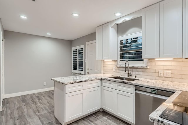 kitchen featuring sink, light wood-type flooring, stainless steel dishwasher, decorative backsplash, and white cabinets