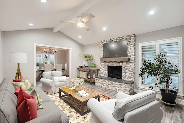 living room with ceiling fan with notable chandelier, a fireplace, hardwood / wood-style floors, and vaulted ceiling with beams