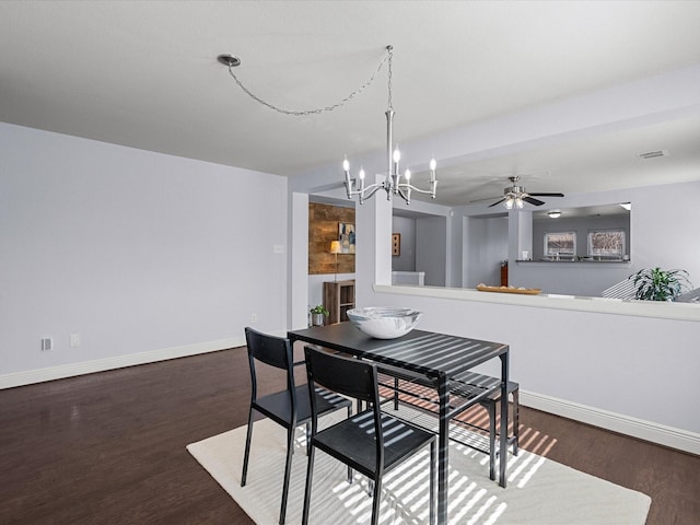 dining room with dark hardwood / wood-style flooring and ceiling fan with notable chandelier