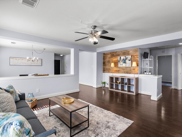 living room with dark hardwood / wood-style flooring and ceiling fan with notable chandelier